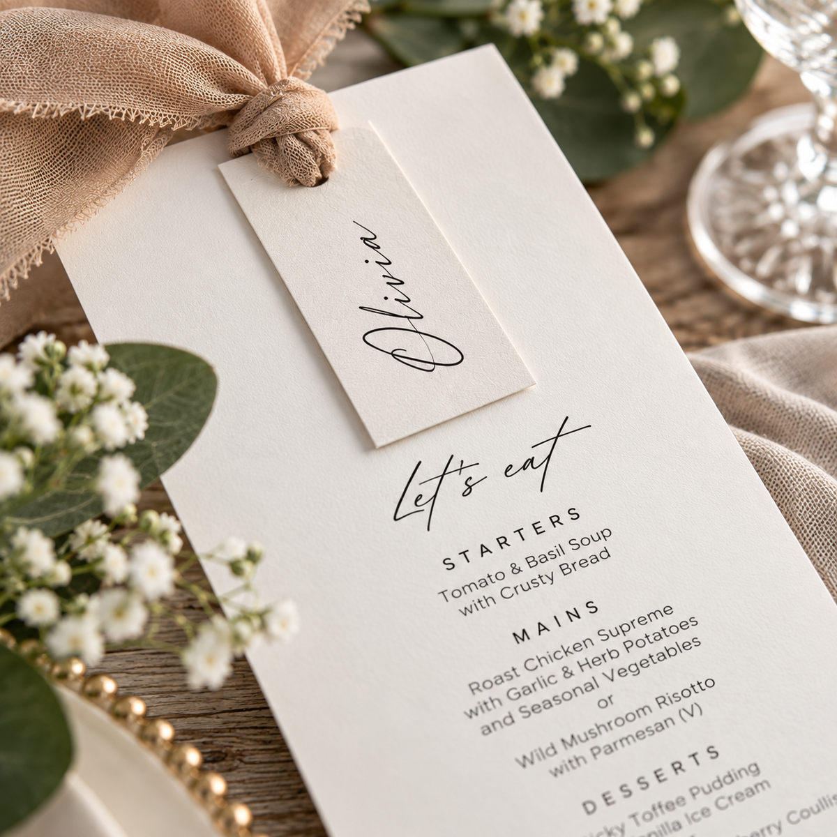 Close-up of personalised wedding menu with Olivia guest name tag, ribbon and printed wedding breakfast choices.